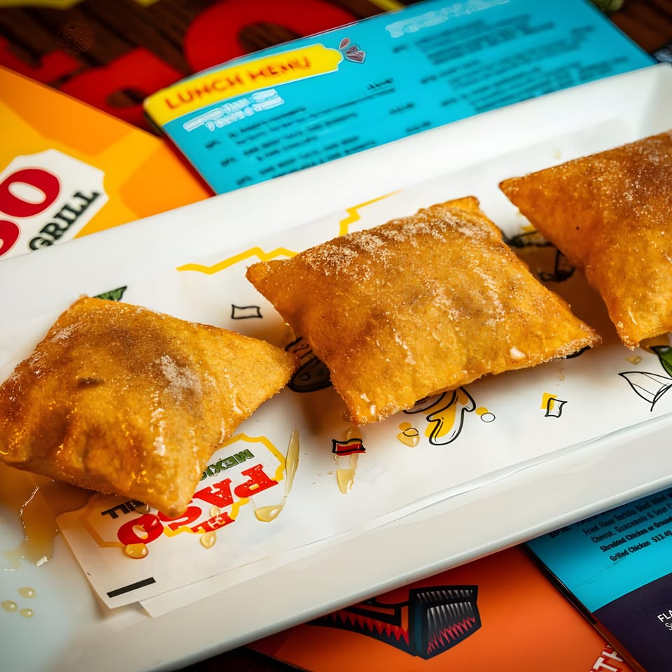 Three golden-brown, sugar-dusted fried pastries, possibly sopapillas, on a white plate with El Paso Mexican Grill branding.