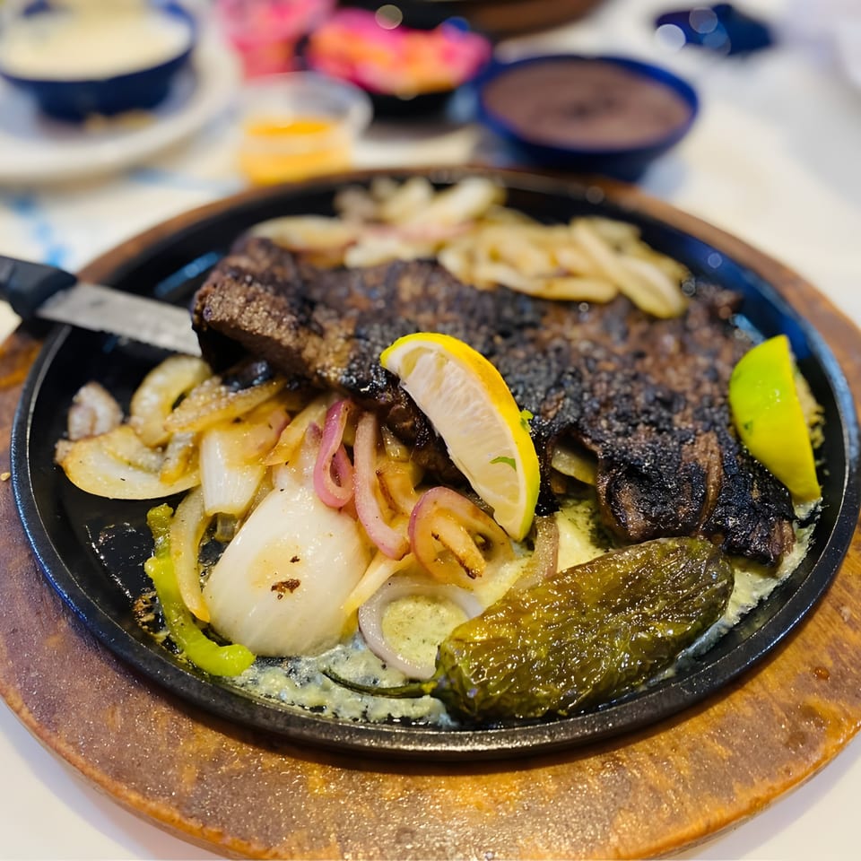Sizzling El Paso Mexican Grill fajitas with steak, onions, peppers, and lime on a cast iron skillet.