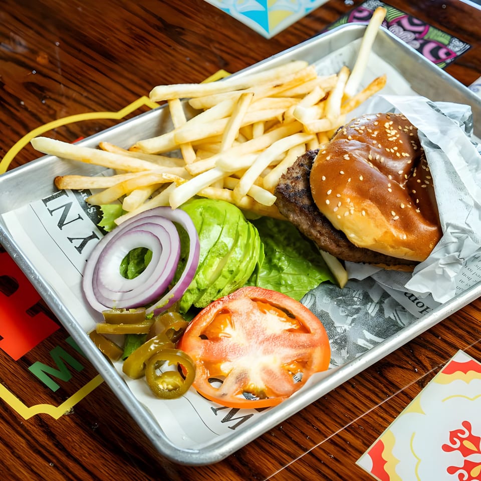 El Paso Mexican Grill's burger with fries, avocado, red onion, tomato, and jalapeños on a tray.